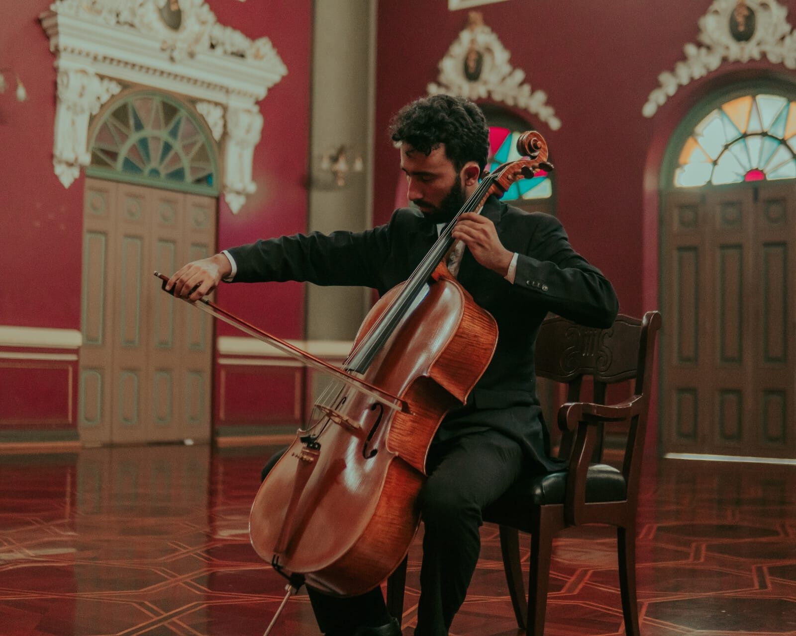 Miguel Berganza tocando el violonchelo en un salón histórico